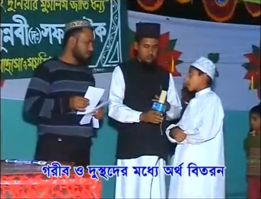 Television footage of a boy receiving assistance on a decorated stage, with a Bengali caption about distributing money to people in need
