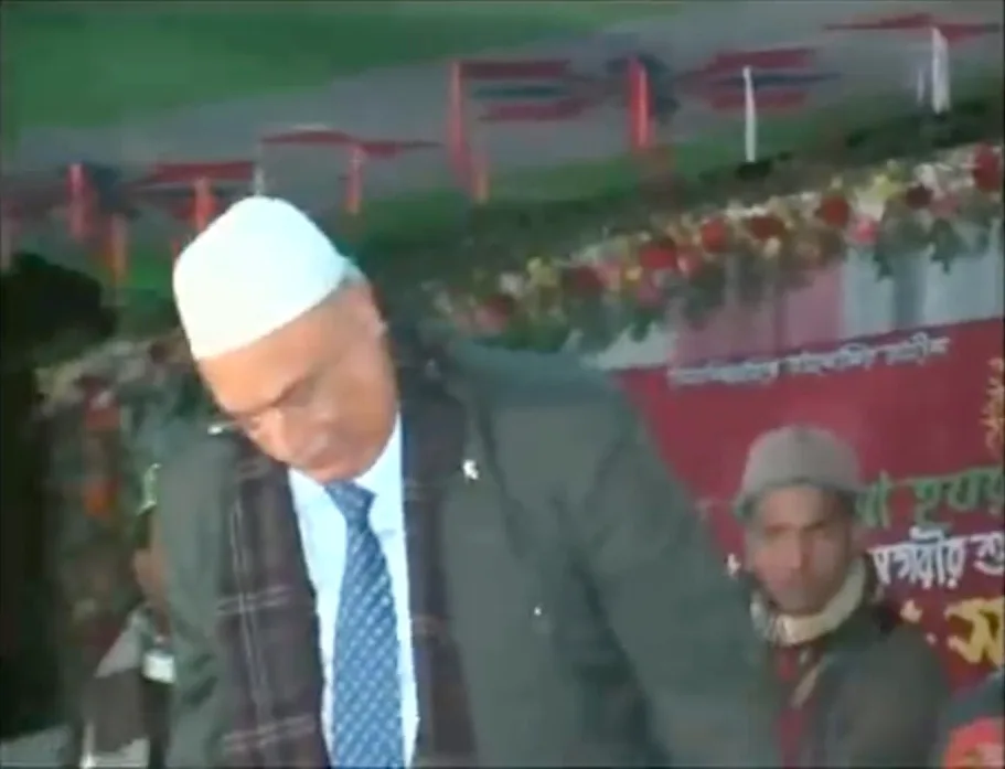 Television footage of a man in a white cap and a suit on a stage